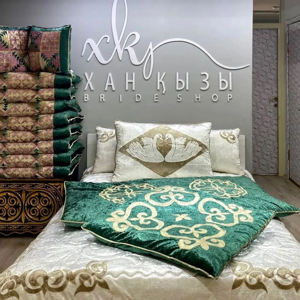 Xan Kyzy bridal shop display with branded backdrop and traditional Kazakh bedding sets