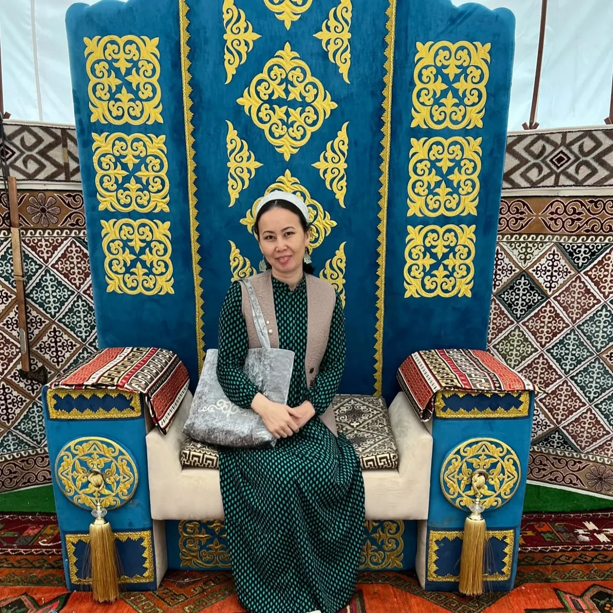 Traditional Kazakh ceremonial seat with embroidered blue and gold textiles at a Xan Kyzy showcase
